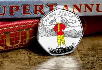 The Rupert Bear Silver Proof 50p Coin reverse leaning against book spines