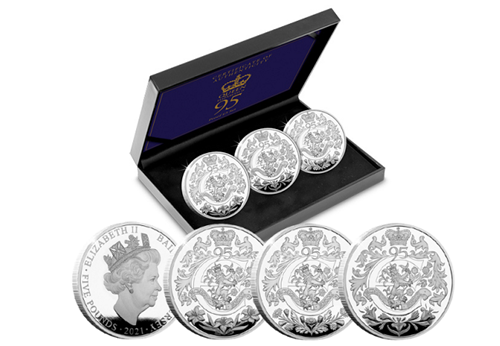 The Queen's 95th Birthday Proof £5 Trio Set in the forefront and in display box in the background